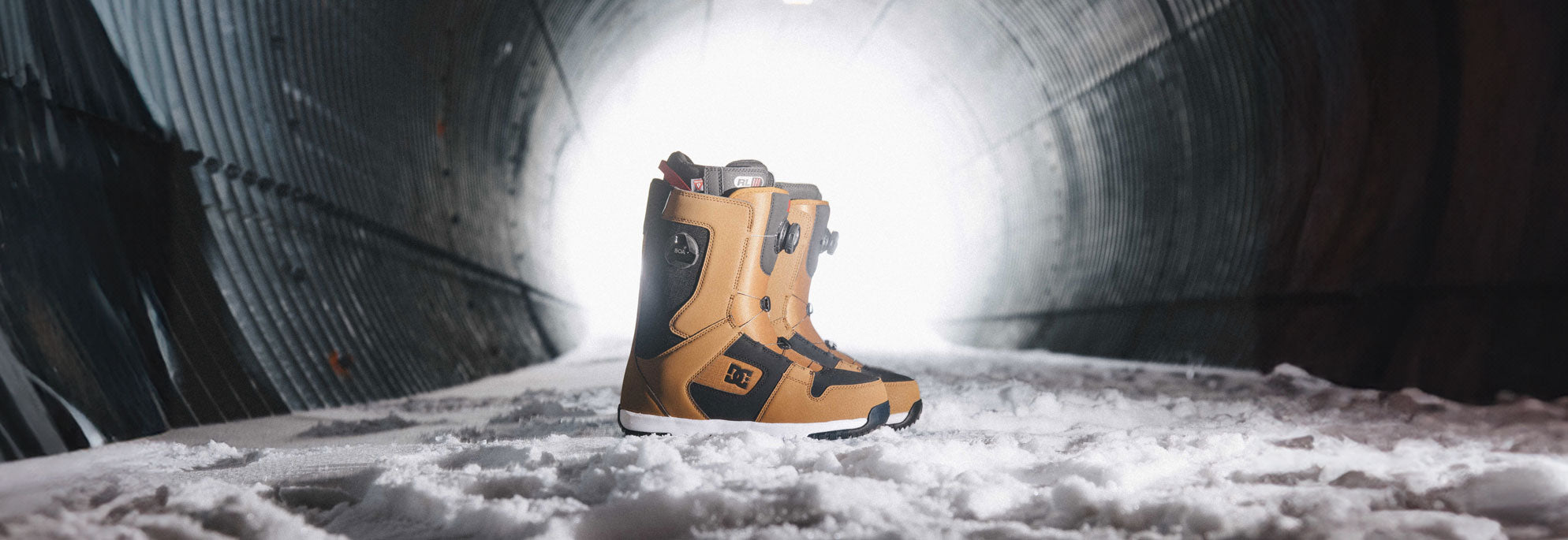 A pair of Dual Zone Boa Fit System Snowboard Boots with a snowy background