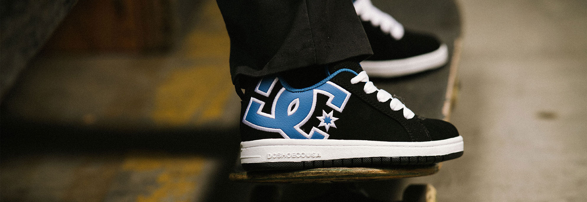 A pair of kids' Court Graffik shoes in black and with a blue logo