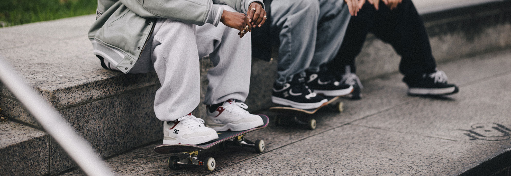 Three kids on skateboards sitting on stoop with DC Shoes on with their skateboards