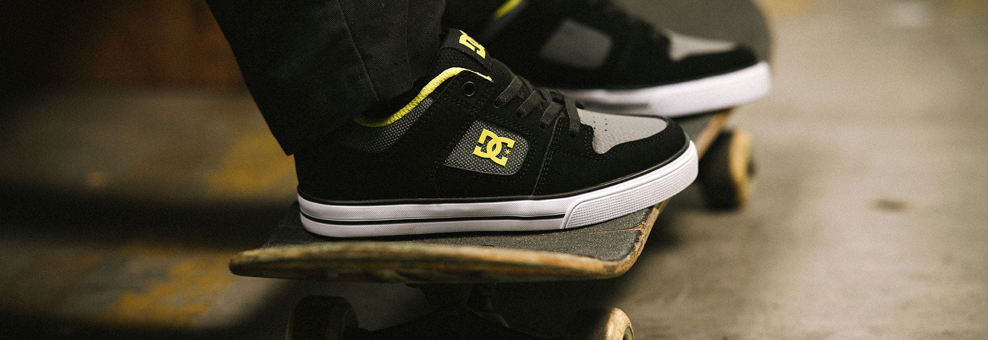 A pair of Pure Kids' shoes worn by a kid on a skateboard and the shoes are black and yellow