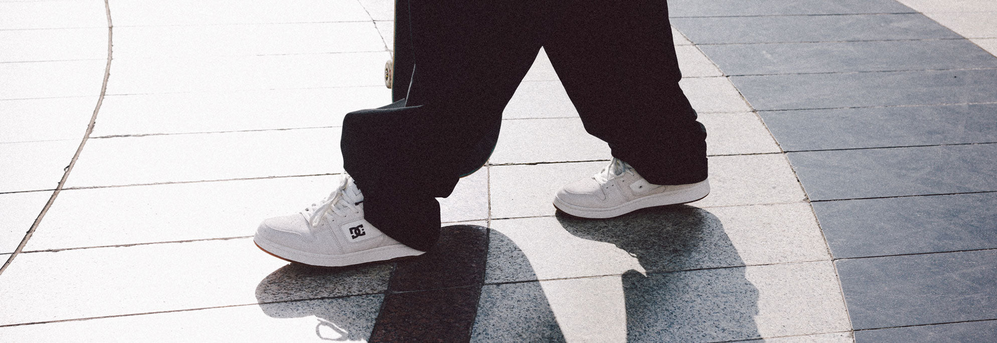 A person walking outside with baggy jeans and white shoes