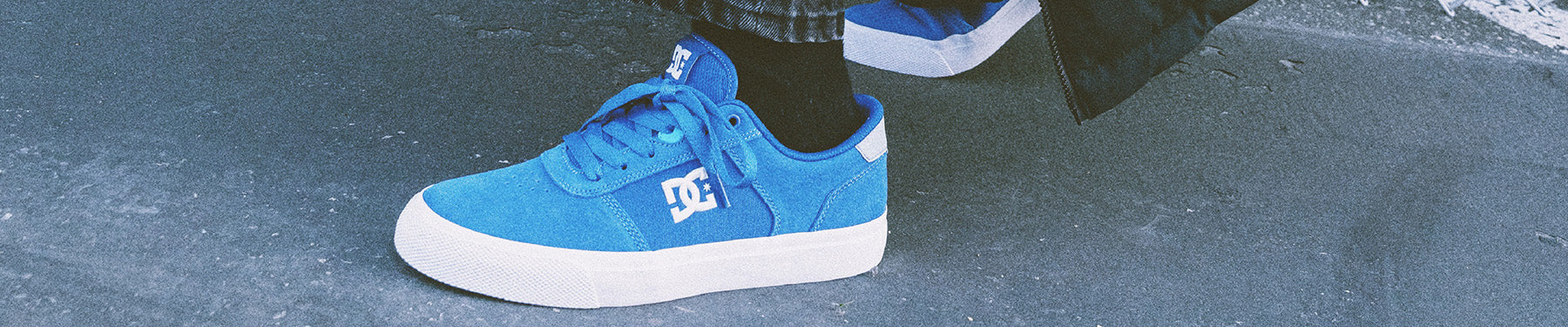 A pair of blue shoes being worn outside