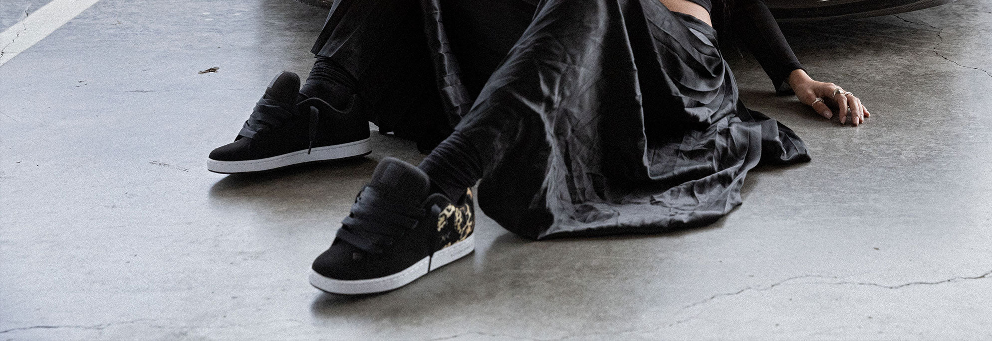 A woman on the floor with a long flowy skirt wearing a pair of DC Shoes shoes