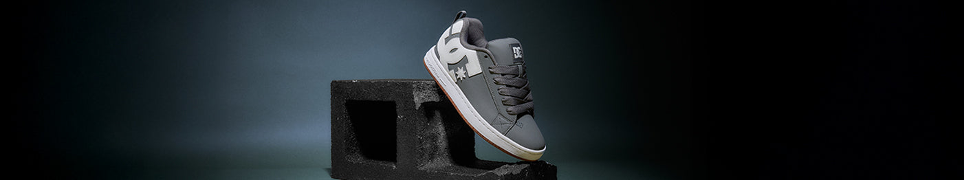 Gray sneaker with white soles on black block on a dark background