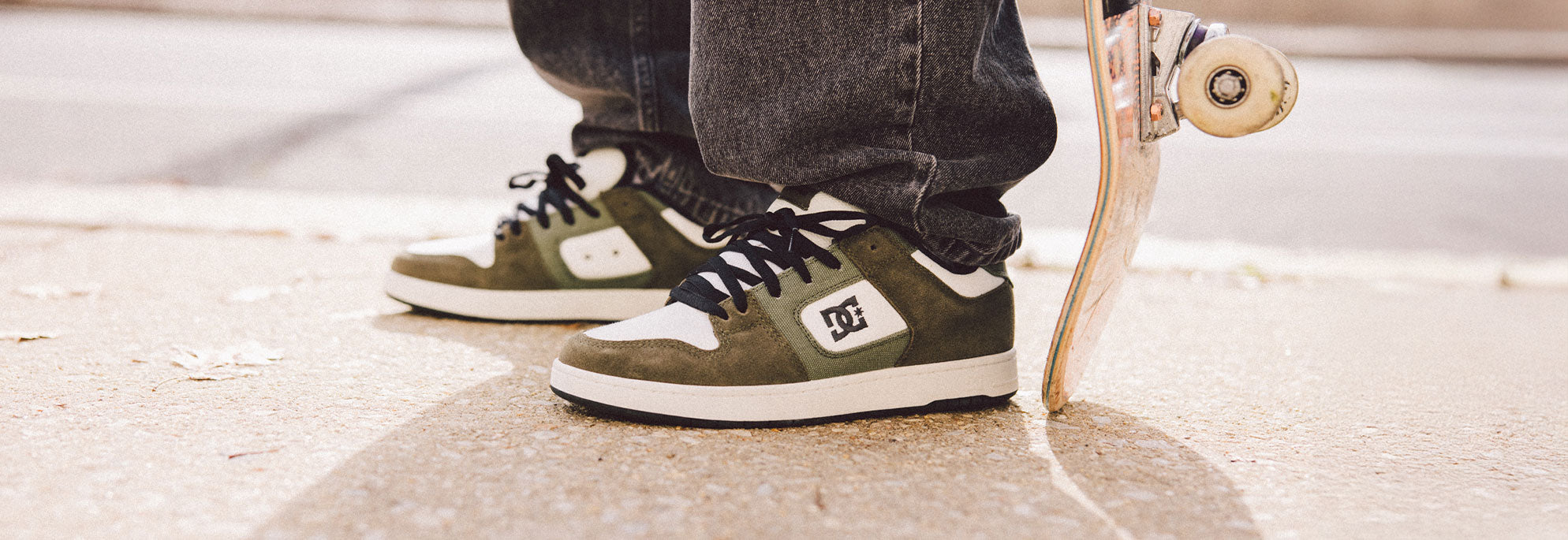 A person wearing DC Shoes and holding down a skateboard