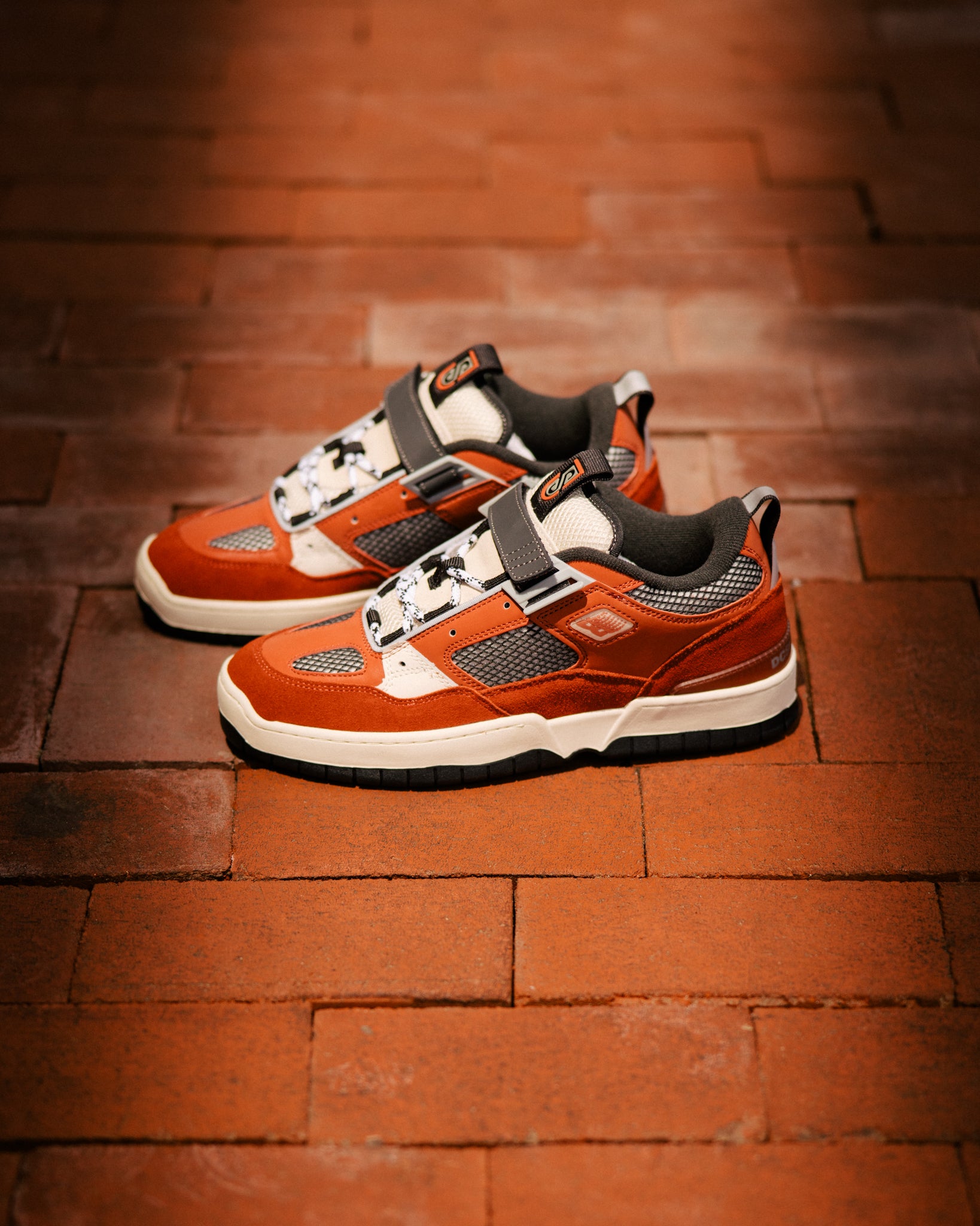 Orange and white sneakers on a brick floor