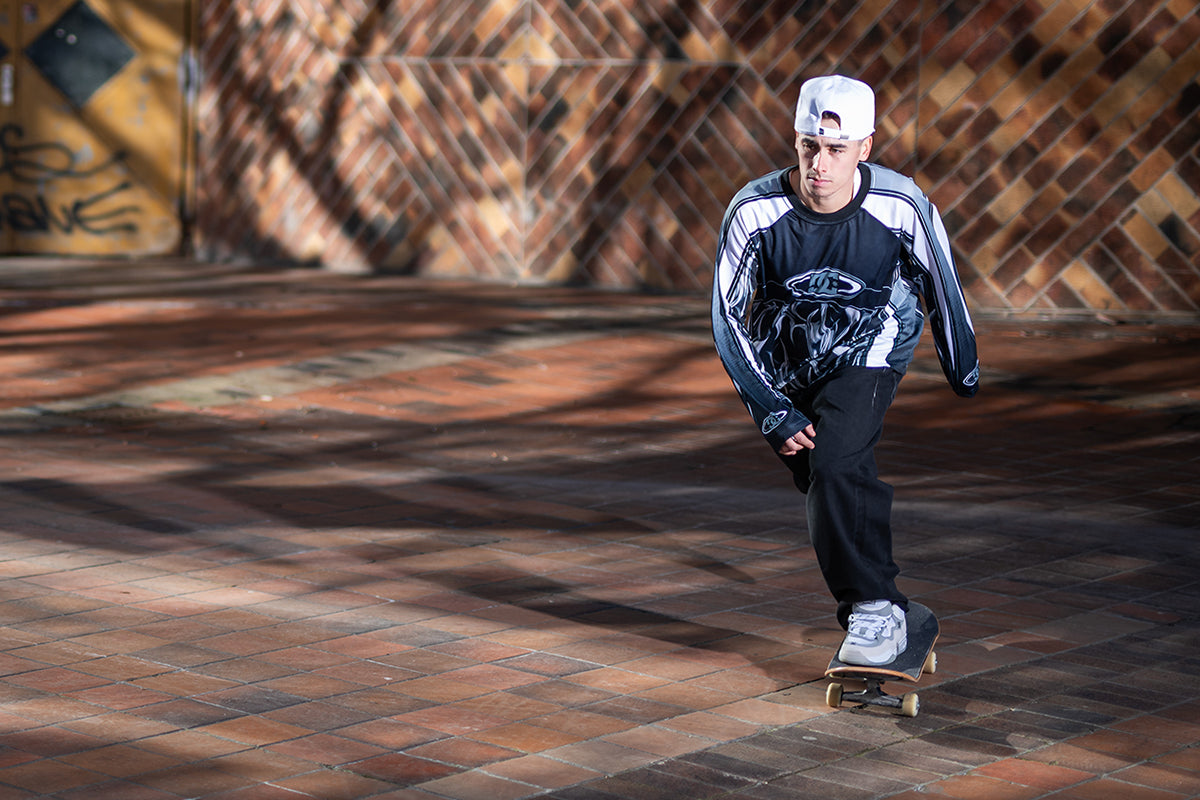 Person skateboarding on a brick pavement with a textured wall in the background