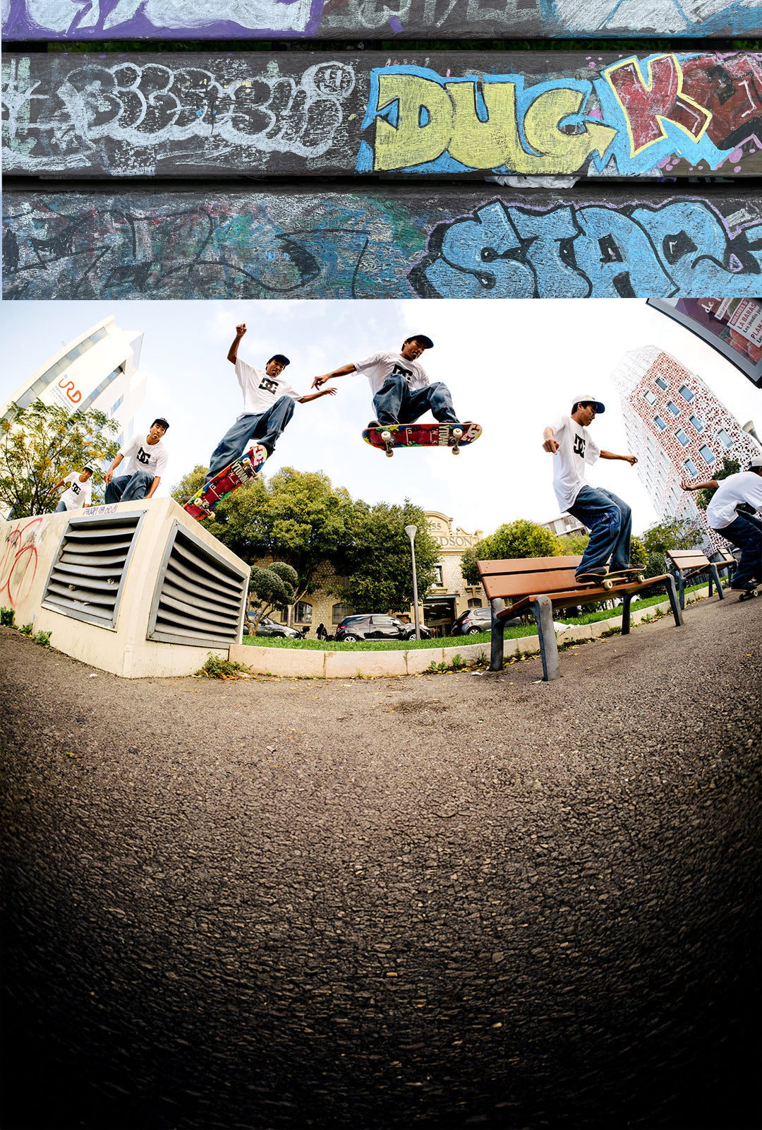 Skateboarders performing tricks in a park with graffiti-covered walls.