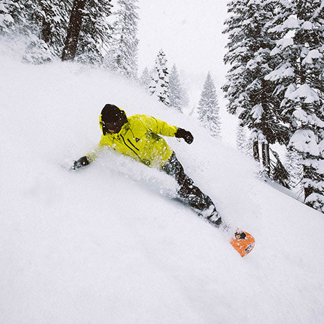 Person snowboarding on the side of a mountain in between trees