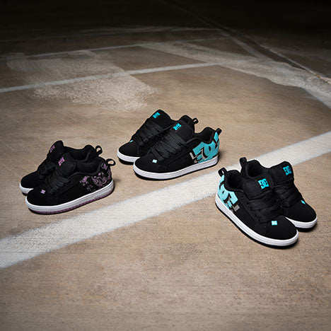 Three pairs of black sneakers with turquoise and pink accents on a concrete floor