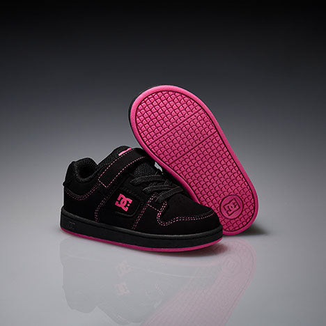 Black and pink DC shoes on a reflective gray surface with a dark background