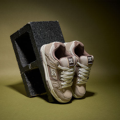 Pair of beige sneakers with a logo on a dark green background