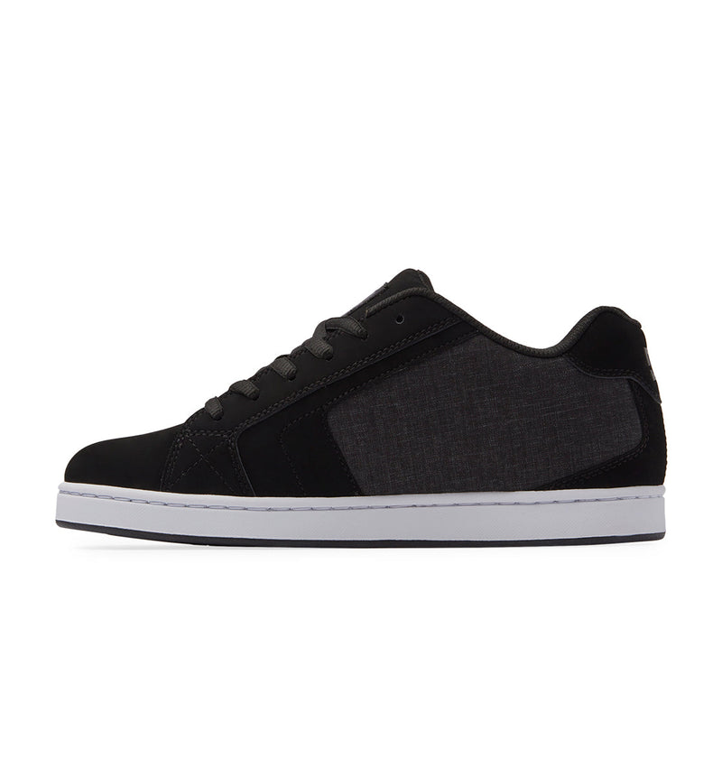 The DC Shoes Men's Net is a black low-top sneaker with a white sole, black laces, and a dark gray fabric side panel. Crafted from durable materials, this puffy shoe is shown in a side view against a plain white background.