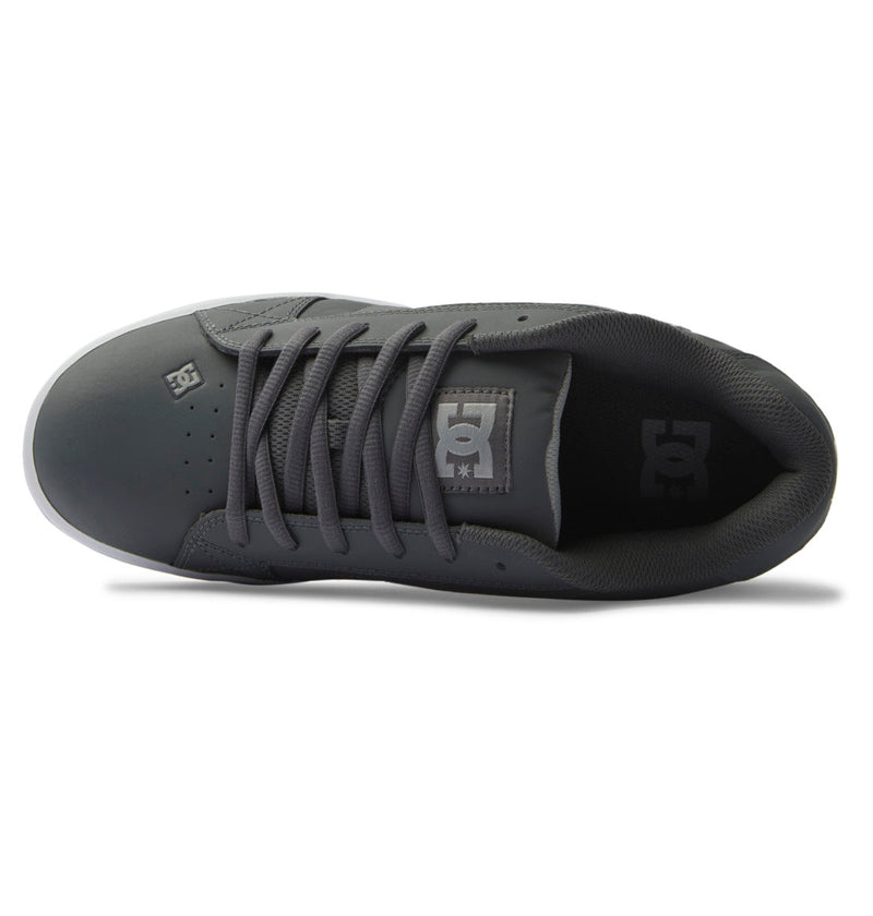 A top view of the DC Shoes Men's Net shows a dark gray puffy sneaker with matching laces, perforated toe box, white sole for comfort, and DC logos on the tongue and side.