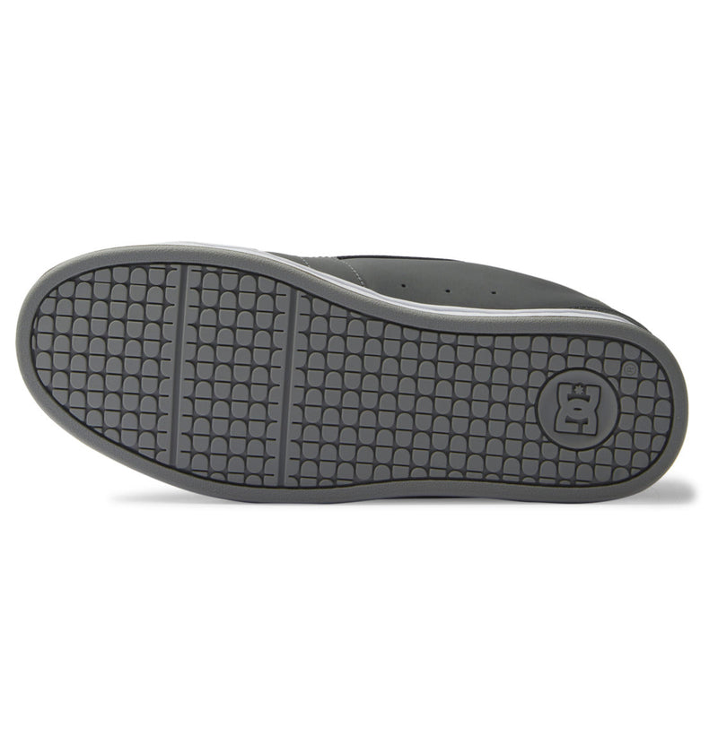 The image displays the sole of the Men's Net Shoes by DC Shoes in black and gray, featuring a textured grid pattern and a circular DC logo near the heel, designed to provide all-day comfort.