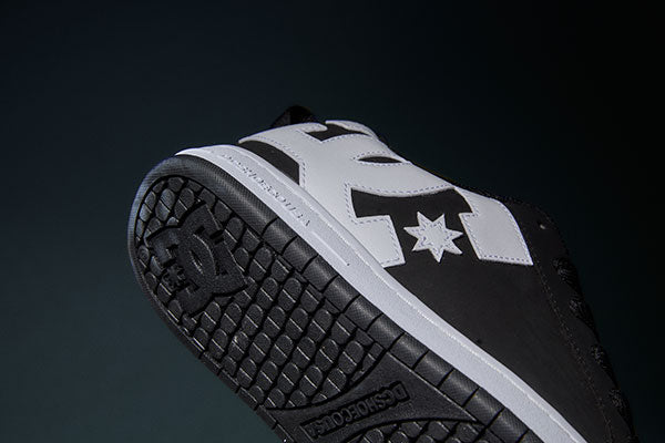 Close up of bottom of black and white sneaker on a dark background