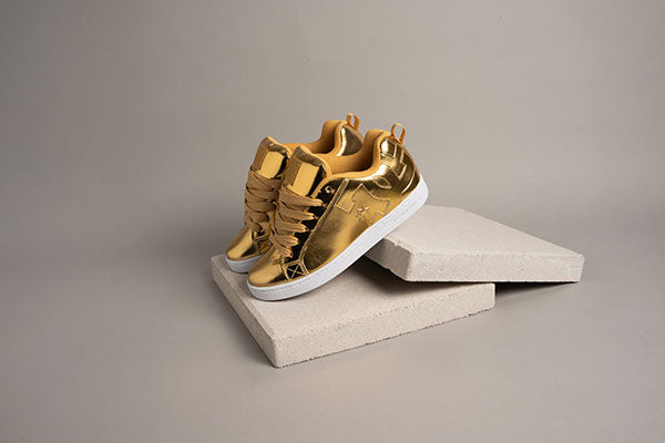 Gold sneakers on a gray surface with a neutral background