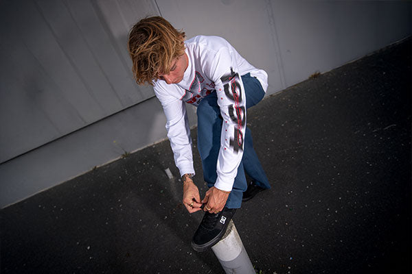 Person tying shoelaces of skate shoes on a concrete surface with a plain background
