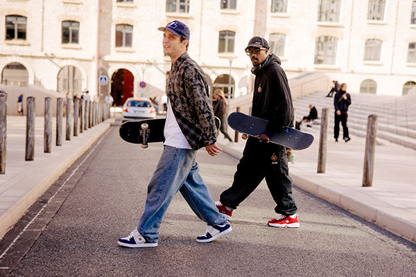 People walking outside with skateboards and blue and white and red sneakers