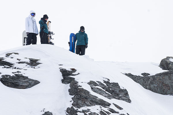 Three people standing on a snowy mountain with ski equipment