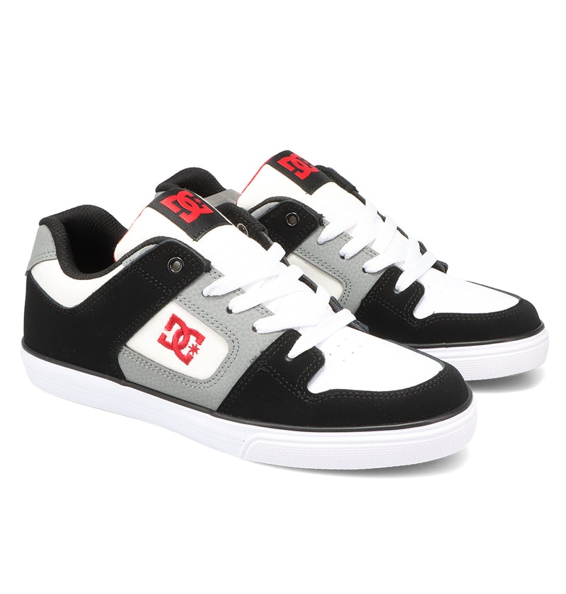A pair of Kids’ Pure Shoes by DC Shoes in black, white, and gray featuring red DC logos, white laces, and white soles are displayed on a white background. Their durable construction ensures they withstand every trick and adventure.