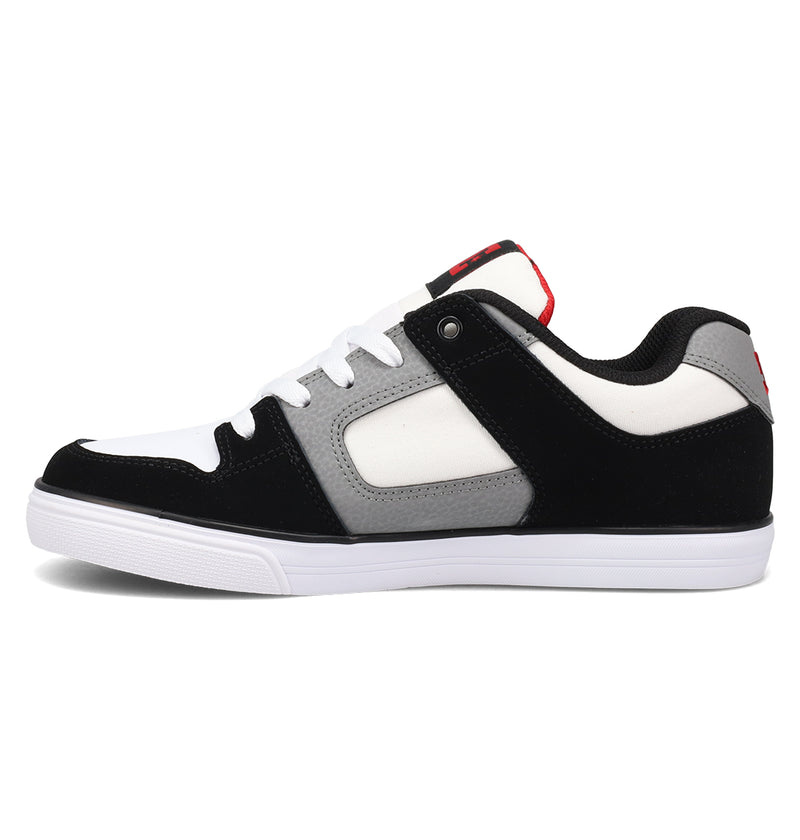 The DC Shoes Kids’ Pure Shoes are durable, low-top skate shoes for kids, featuring a white sole, black suede toe and heel, gray mid-panel, comfortable white laces, and bold red accents on the tongue and heel.