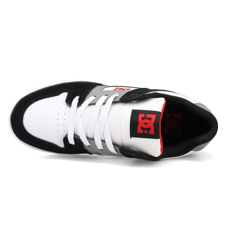 The Kids’ Pure Shoes by DC Shoes feature a black, white, and gray color scheme and are shown from above with white laces, a perforated toe box, and the signature red DC logo on the black tongue—stylish and durable skate shoes designed for kids’ comfort.