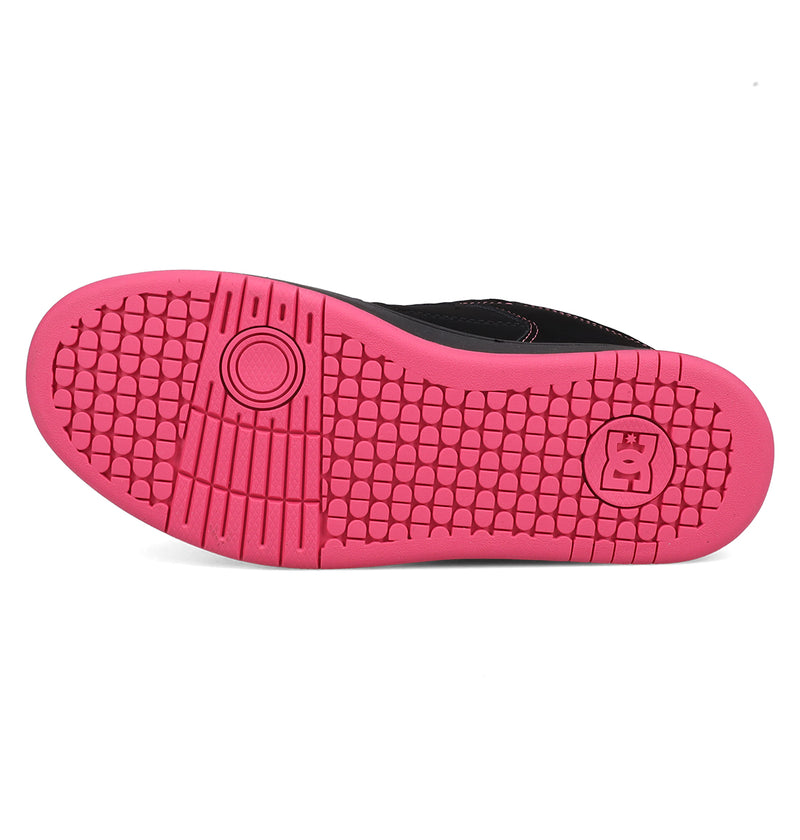 The image features the sole of DC Shoes Women's Manteca 4, showing a bright pink color, textured grip pattern, and a circular crown logo near the heel. The shoe's upper is black.