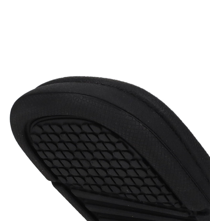 Close-up view of the black sole on DC Shoes Kids' Bolsa Slides, featuring a textured, grid-like tread pattern designed for grip and comfort.