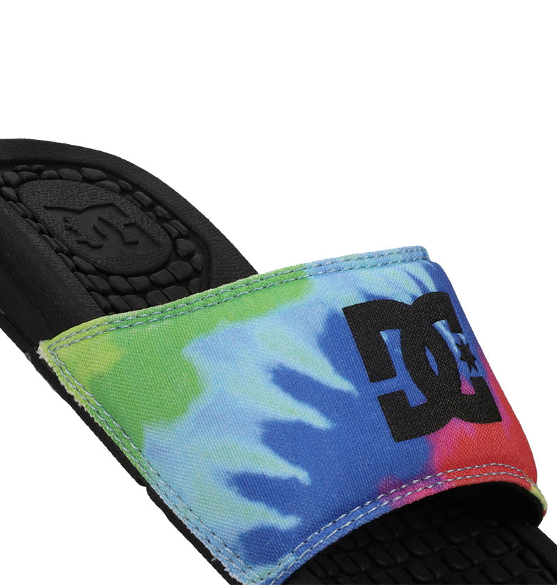 Close-up of Kids' Bolsa Slides by DC Shoes, featuring a comfy black sole and colorful tie-dye strap with a bold black DC Shoes logo—ideal kids sandals for vibrant summer style.