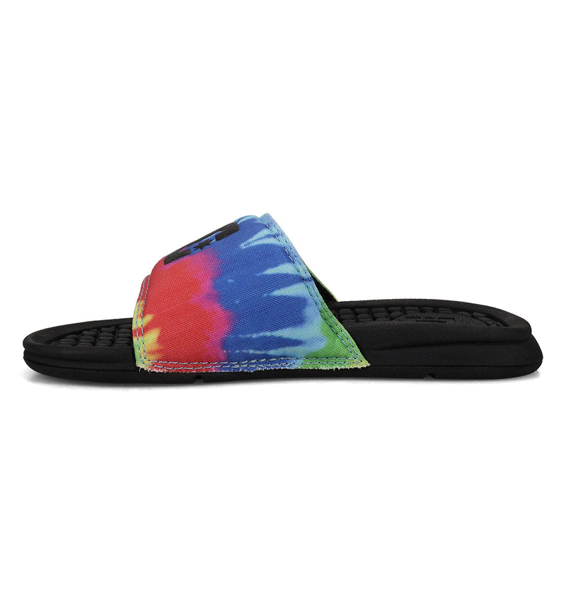 The DC Shoes Kids' Bolsa Slides feature a black sole and a vibrant tie-dye strap in red, blue, green, and yellow. Displayed from the side on a white background, these slides offer comfort and standout style.