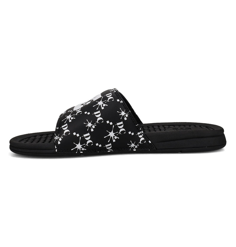The Men's Bolsa Slides from DC Shoes feature a black design with a patterned strap adorned with white snowflake-like designs and stylized letters. The textured footbed ensures extra grip and comfort, making them ideal for post-skate sessions.