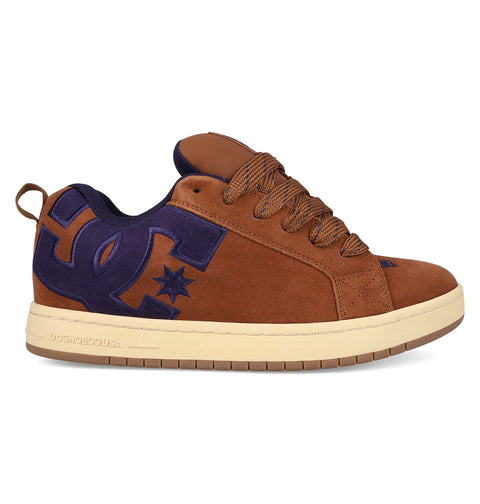 The DC Shoes Men's Court Graffik SE is a brown suede skate shoe with a puffy silhouette, tan sole, brown laces, dark blue interior lining, and a large dark blue DC logo with a star on the side.