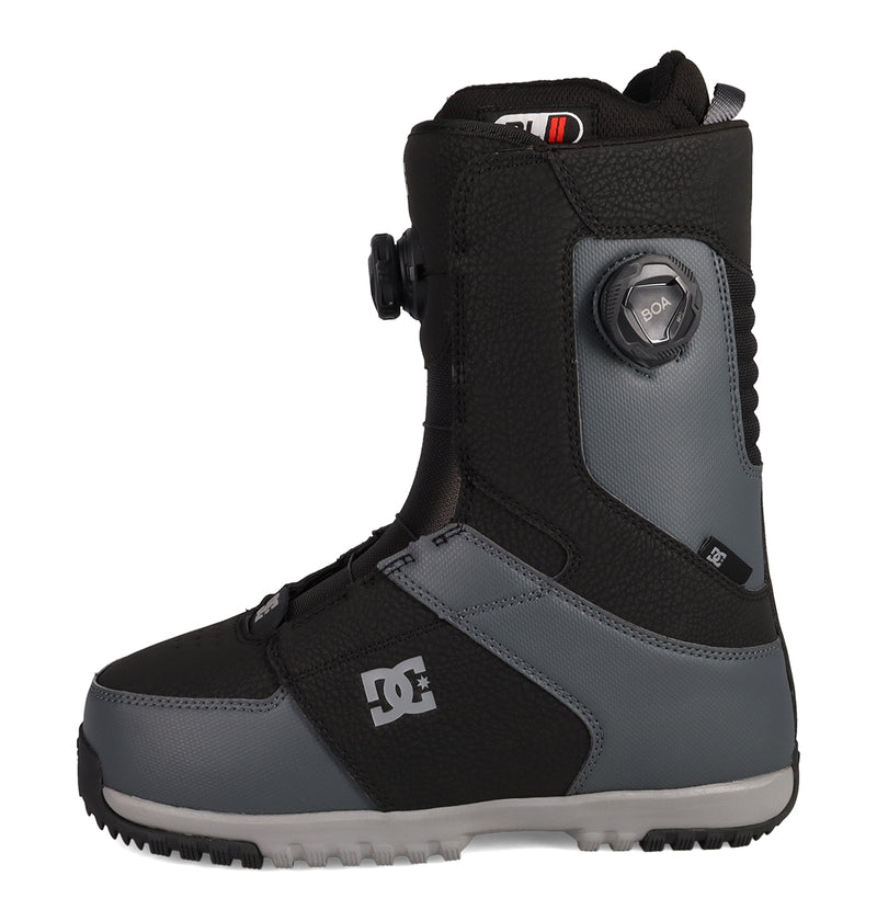 A side view of the Men’s Control Snowboard Boots by DC Shoes in black and gray, showcasing the latest snow boot innovation with a Dual Zone BOA Fit System and the DC logo, displayed against a white background.