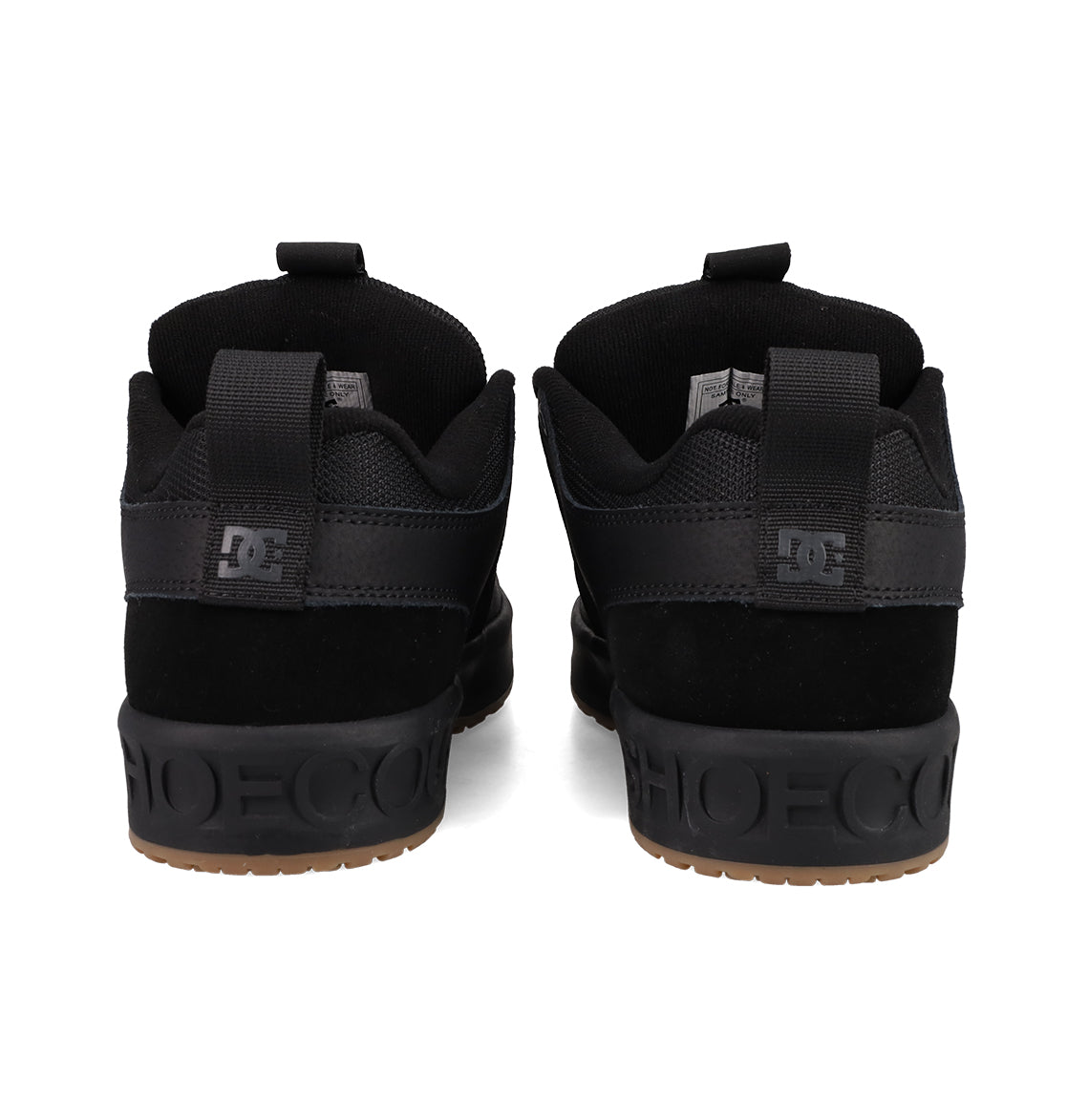 A pair of Men's Lynx OG Shoes by DC Shoes, in black, viewed from the back with DC logos on the heels, SHOECOUSA embossed on black midsoles, and gum rubber outsoles—an iconic skateboarding favorite.
