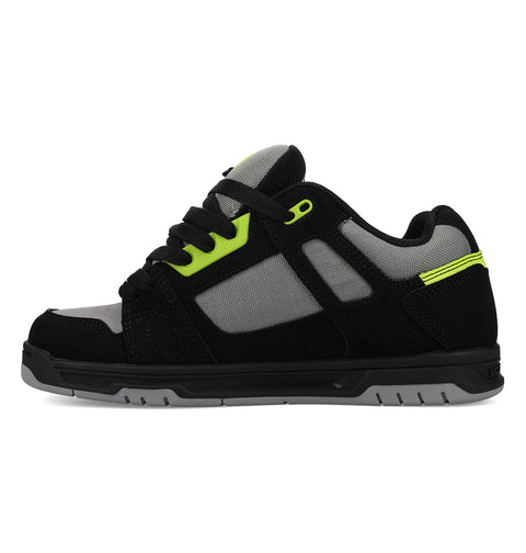 The Men's Stag Shoes by DC Shoes feature a black and gray design with neon green accents, black laces, mesh panel upper, durable cupsole, and rubber sole; displayed side profile on a white background.