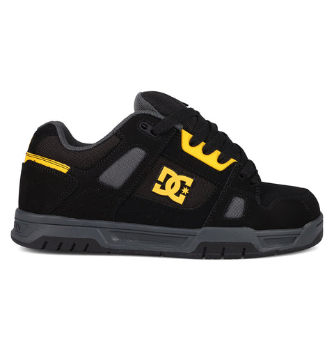 The DC Shoes Men's Stag features a black and grey design with yellow accents, a yellow side DC logo, black laces, and a durable cupsole. Styled for skate culture, it's displayed in side profile against a white background.