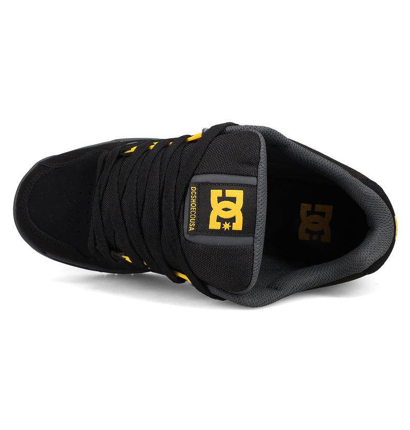 Top view of Men's Stag Shoes by DC Shoes in black, featuring black laces, gray inner lining, and yellow accents on the tongue and side logos. Features a durable cupsole for lasting performance in skate culture.