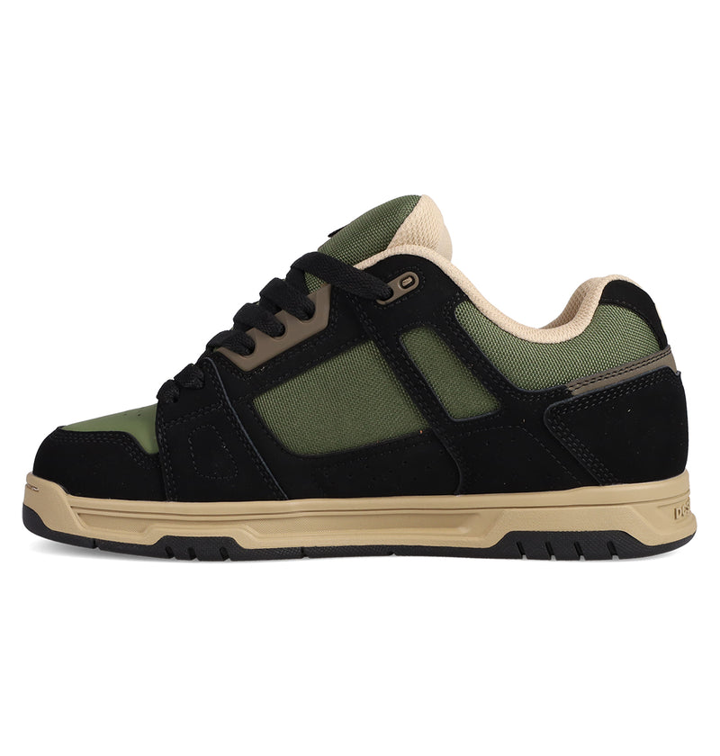 The DC Shoes Men's Stag Shoes are black, green, and beige low-top skate shoes with a thick cupsole, mesh panels, suede overlays, black laces, and a padded beige collar. Shown in profile on a white background. Inspired by the classic Stag style.
