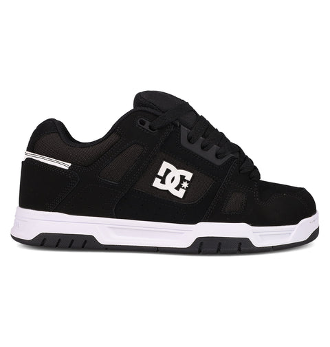 The Men's Stag Shoes by DC Shoes are shown in side profile against a white background, featuring a black upper with a white side logo, black laces, and a thick white and black cupsole—ideal for skate culture enthusiasts.