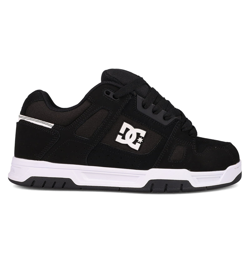 The Men's Stag Shoes by DC Shoes are shown in side profile against a white background, featuring a black upper with a white side logo, black laces, and a thick white and black cupsole—ideal for skate culture enthusiasts.