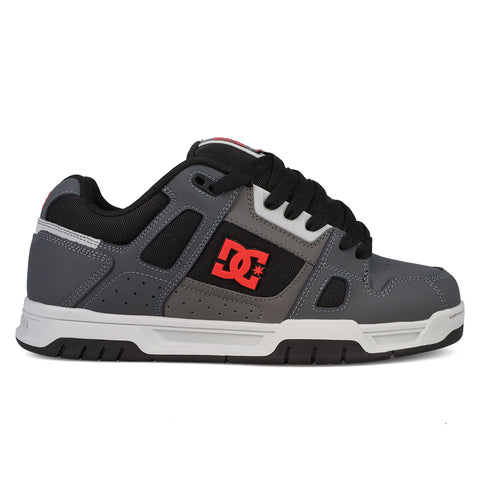 The Men’s Stag Shoes from DC Shoes are gray and black skate shoes featuring a red DC logo on the side, black laces, and a white and black sole. Designed with cupsole construction for enhanced durability, these low-profile sneakers offer padded support, perfectly embodying classic skate culture style.