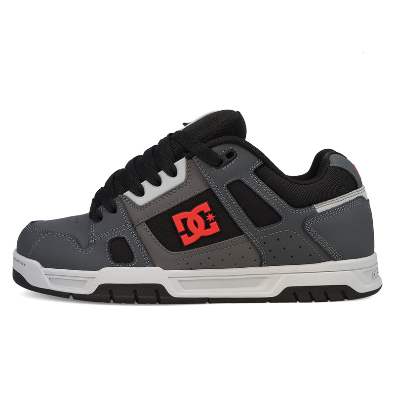 The Men’s Stag Shoes by DC Shoes feature a gray and black design with black laces, a white sole, and a red DC Shoes logo on the side. Drawing inspiration from skate culture, these shoes include a padded collar, visible stitching details, and durable cupsole construction for long-lasting comfort and grip.