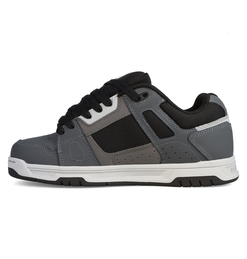 A gray and black DC Shoes Men’s Stag sneaker with white accents, black laces, and a white sole—shown from the side on a plain white background—features cupsole construction inspired by skate culture, in the classic style of DC Stag designs.