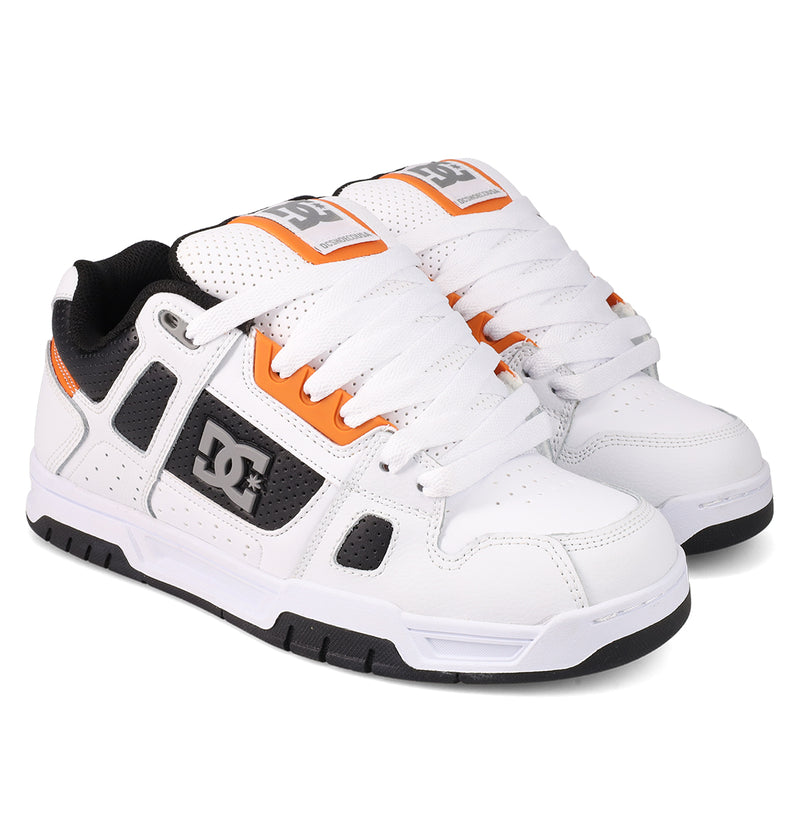 A pair of DC Shoes Men's Stag in white with black and orange accents, thick white laces, and durable black cupsoles, styled side by side on a white background—ideal for skate culture.