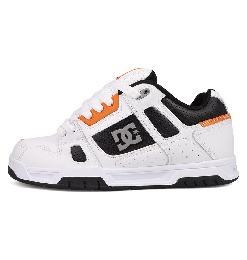 The Men's Stag Shoes by DC Shoes feature a white and black design with orange accents, the DC Shoes logo on the side, a durable cupsole for grip, black sole, white laces, and perforated detailing for ventilation. Ideal for skate enthusiasts.