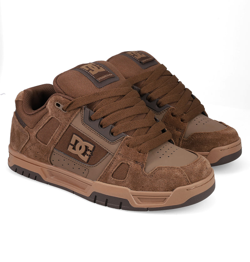 A pair of Men's Stag Shoes by DC Shoes in brown, featuring suede and leather panels, thick laces, and durable cupsole construction, shown on a white background.