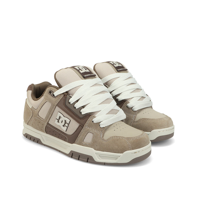 The DC Shoes Men's Stag Shoes in beige and brown feature white laces, prominent DC logos on the side and tongue, and a durable cupsole for lasting wear, displayed side by side on a white background.