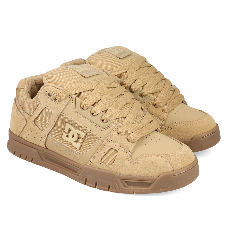 A pair of tan DC Shoes Men's Stag skate shoes with thick laces, padded tongues, cupsole construction, textured soles, and DC logo on the side panels, shown against a white background.