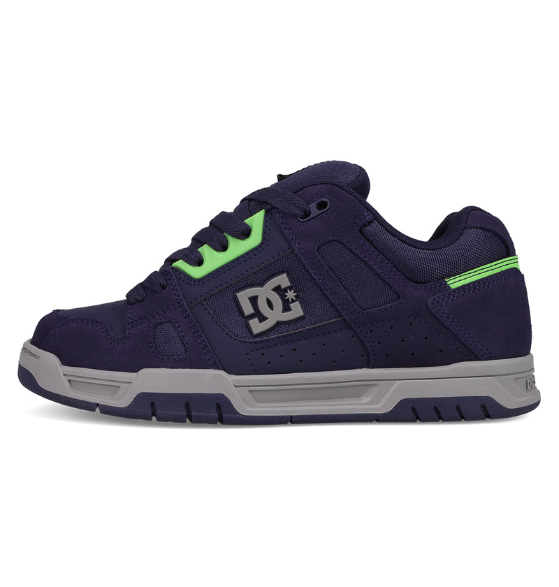 The Men's Stag Shoes by DC Shoes feature navy blue and gray tones, black laces, neon green accents, a silver DC logo, and durable cupsole construction. Shown in profile against a white background—ideal for skate culture fans.
